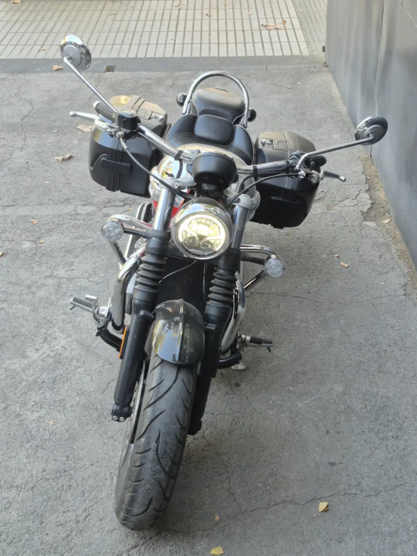 Triumph Speedmaster 1200 2023 frontal directo alforjas laterales rojo negro